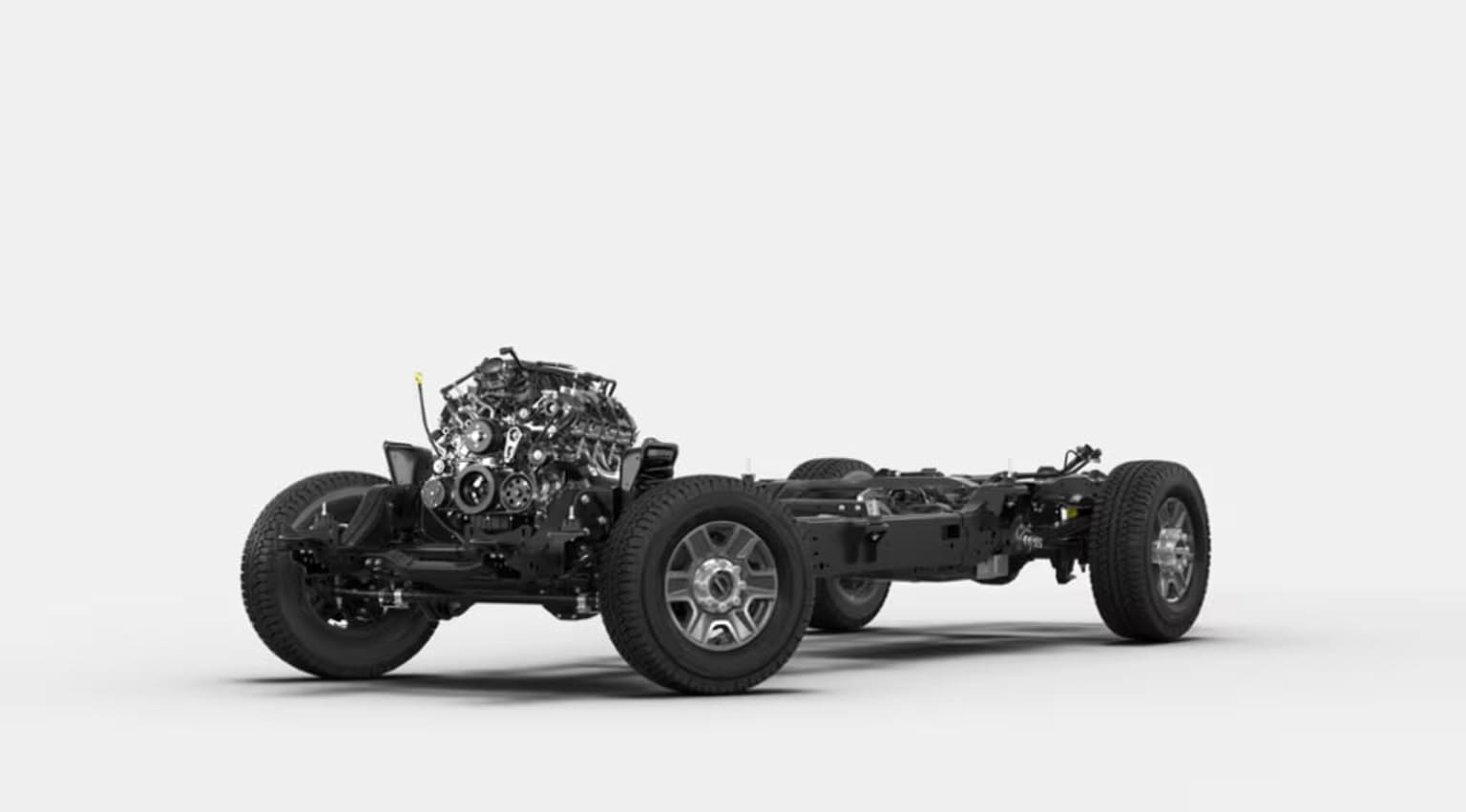 Vintage black-and-white automobile chassis with large wheels and an exposed engine on a plain background.