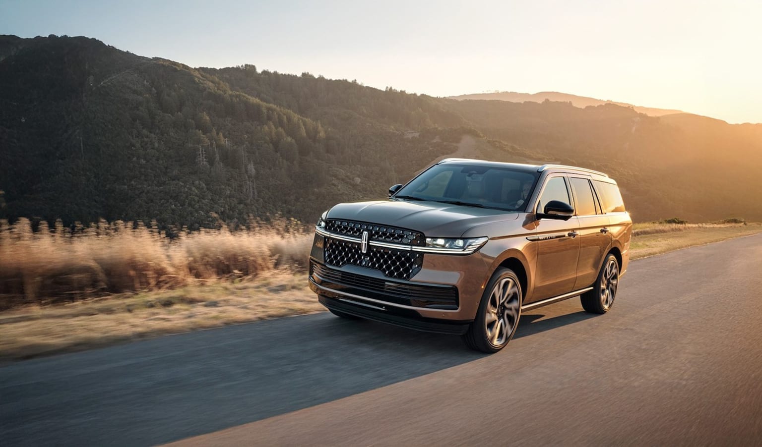 2025 Lincoln Navigator Black Label in exterior color Sunrise Copper driving away as the sunset (1)