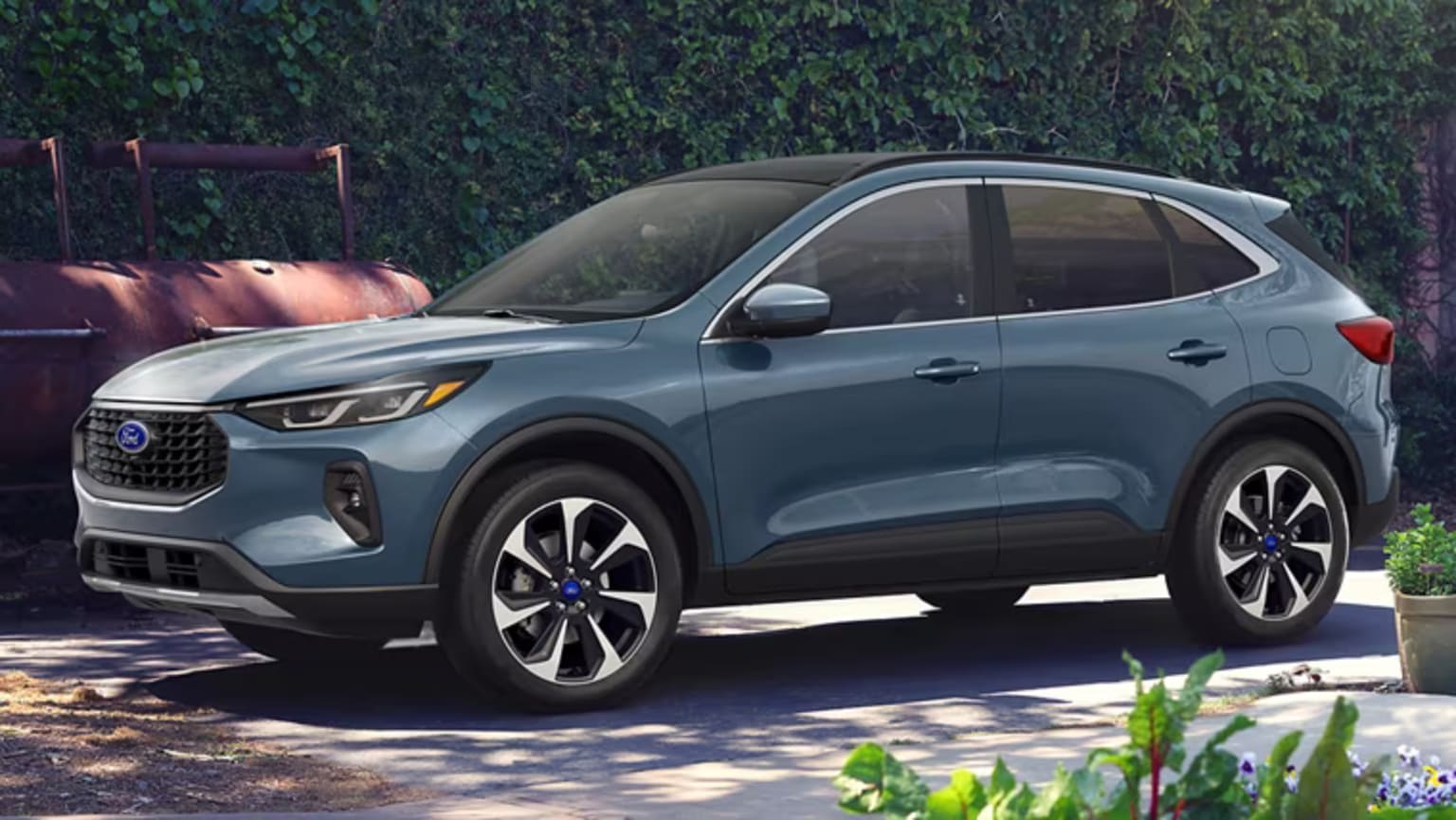 An SUV parked on a driveway with greenery and a wooden fence in the background.