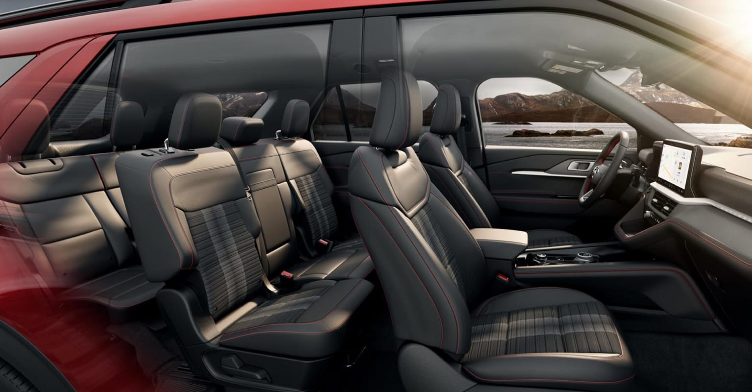 Interior of a spacious vehicle with comfortable-looking seats and a large windshield offering a panoramic view of a scenic landscape in the background.