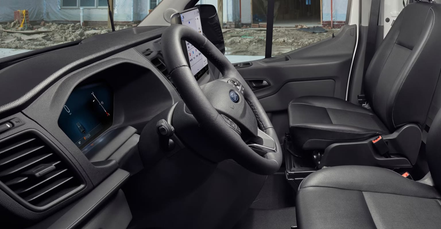 Image of a vehicle interior with a steering wheel, dashboard, and seats visible, set against a construction site or outdoor backdrop.