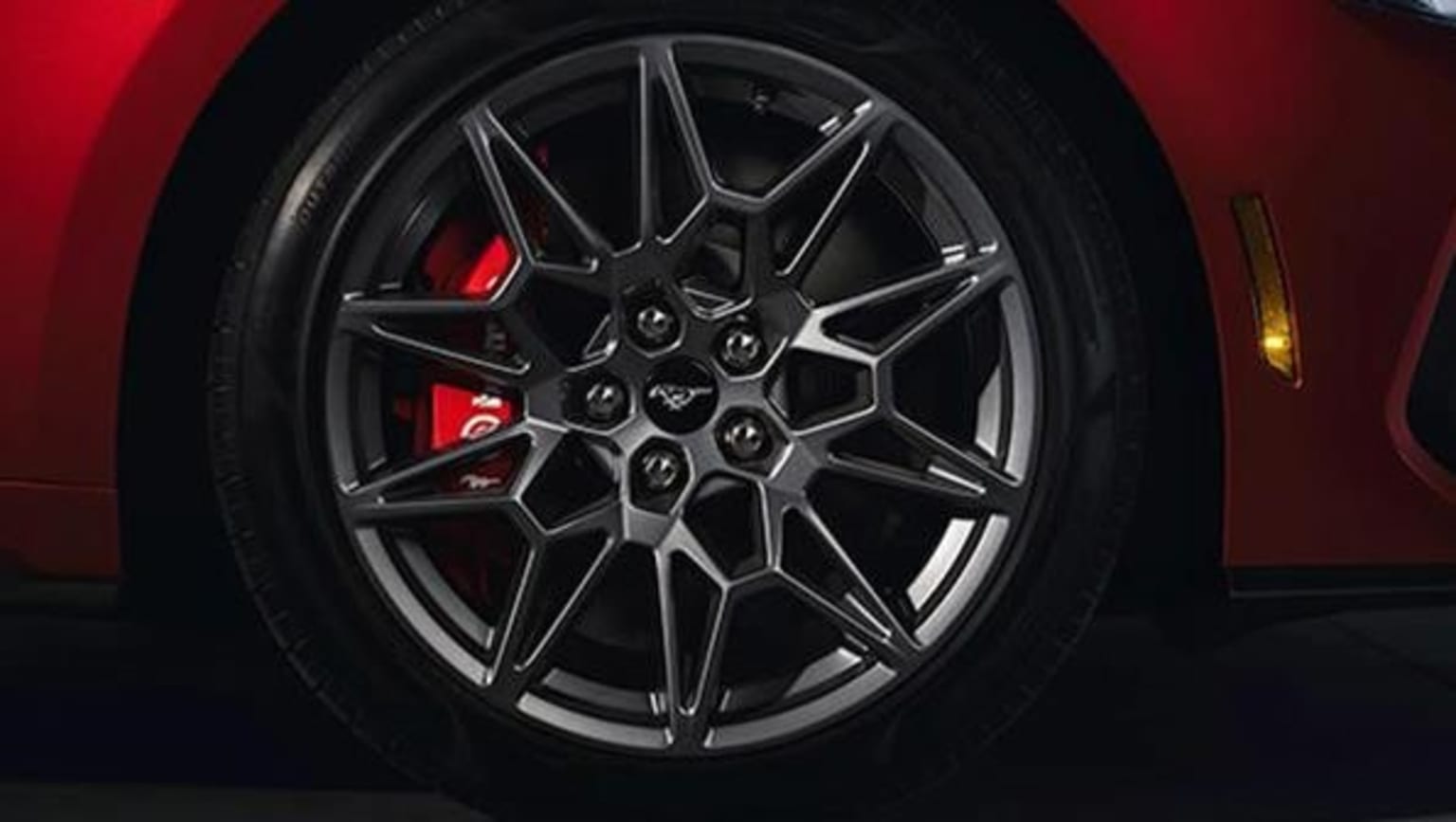 Close-up view of a sleek, high-performance car's alloy wheel with a black and red design against a dark background.