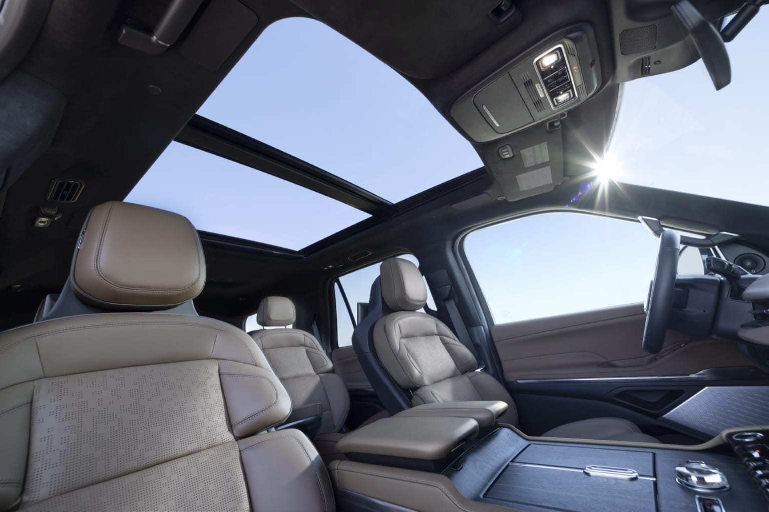 The image shows the interior of a vehicle with a panoramic sunroof, light-colored upholstered seats, and a modern dashboard and center console.