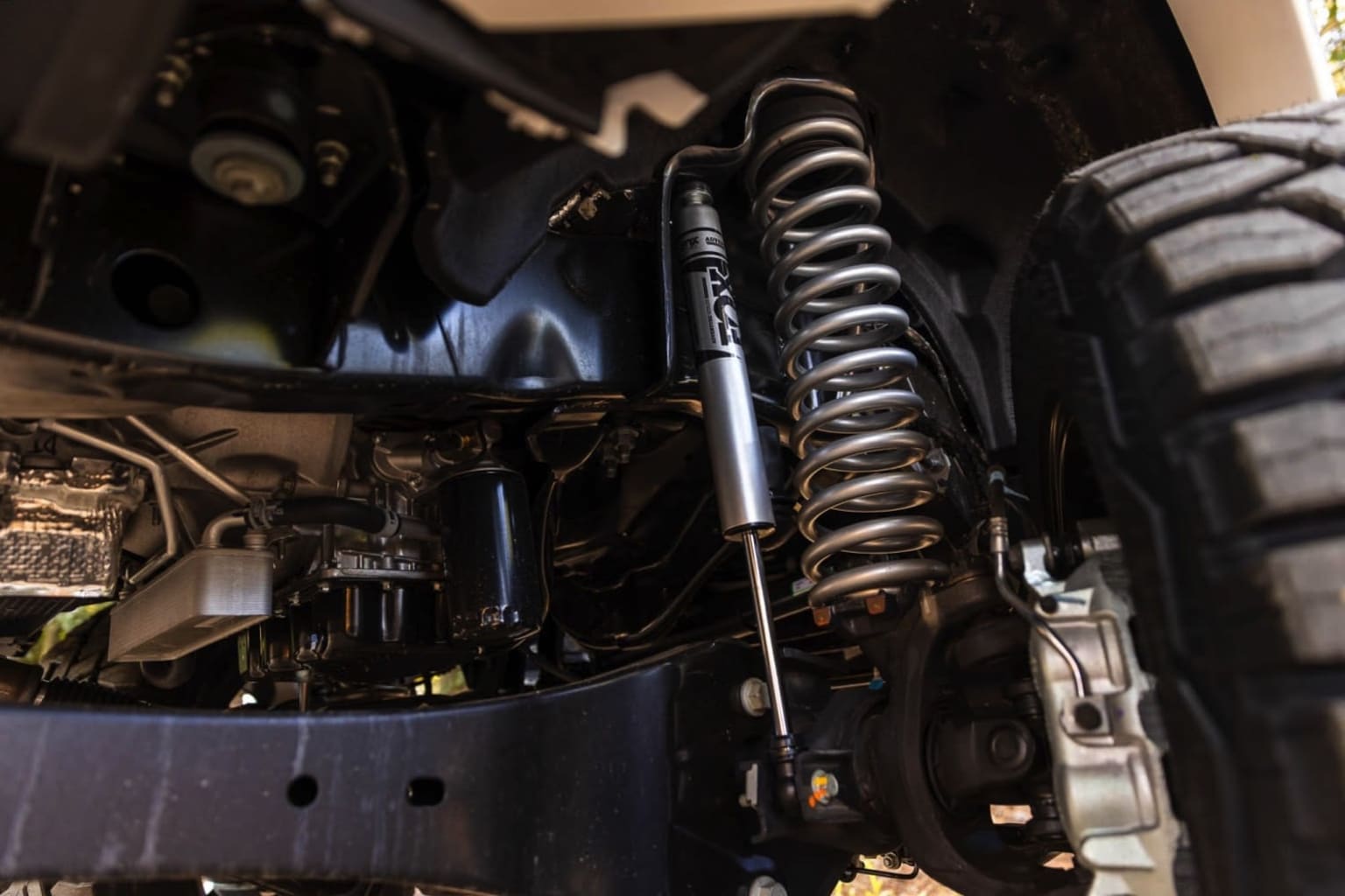 Interior of a vehicle with a close-up view of the suspension system and various mechanical components, including coil springs and shock absorbers.