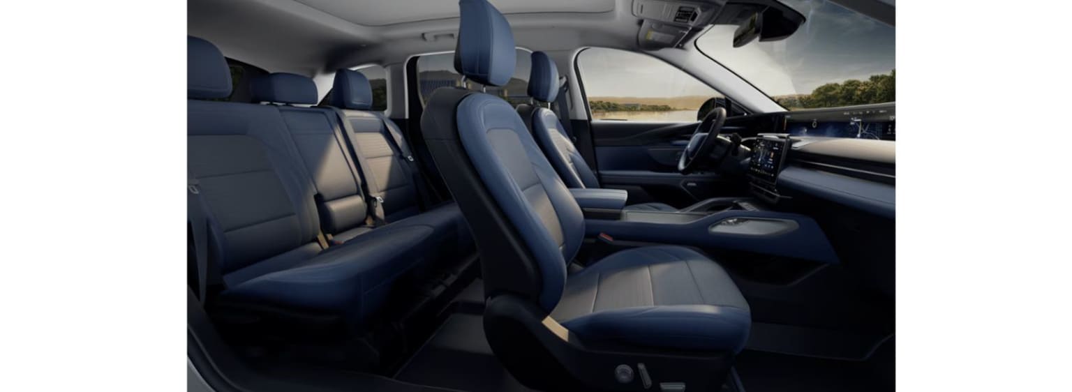 Interior of a vehicle with dark leather seats and a dashboard visible in the foreground, with a scenic landscape visible through the windshield in the background.