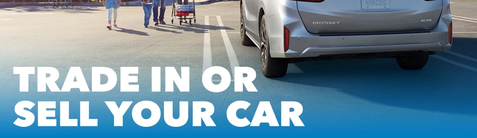 White text with bold capital letters displays "TRADE IN OR SELL YOUR CAR" on top of a silver minivan parked in a lot. People and a shopping cart can be seen in the background.