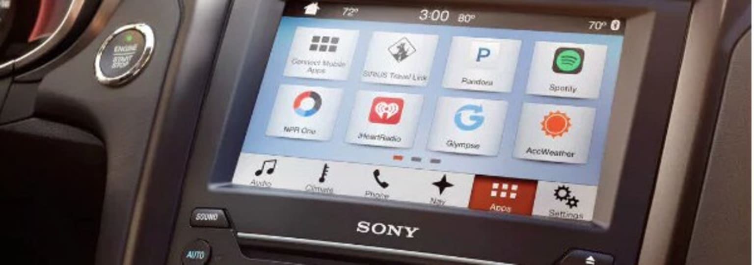 a close up of a car dashboard with various app icons on the display of the car's radio