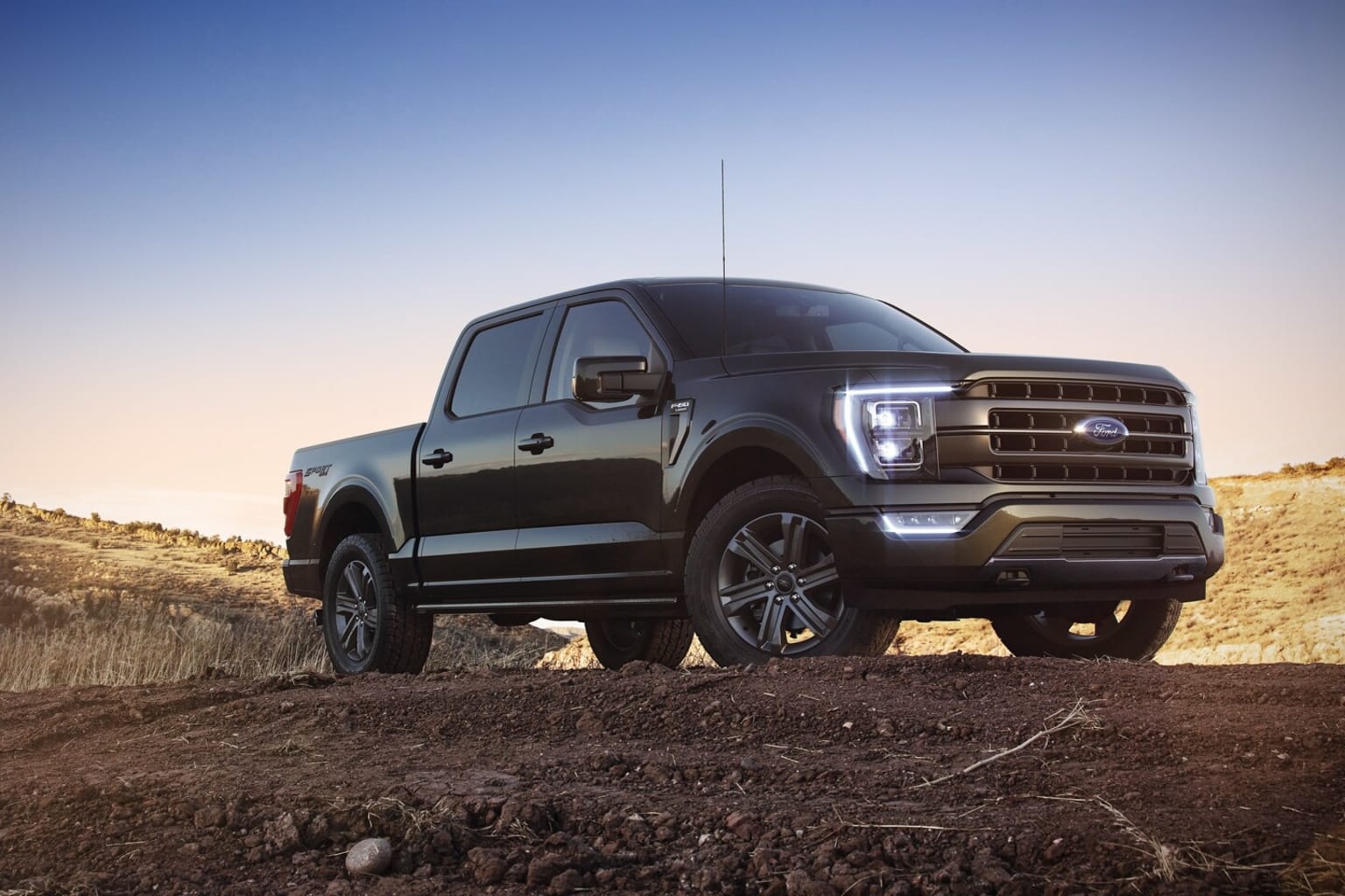 A large black pickup truck parked on a dirt hillside, with its front end facing the viewer.