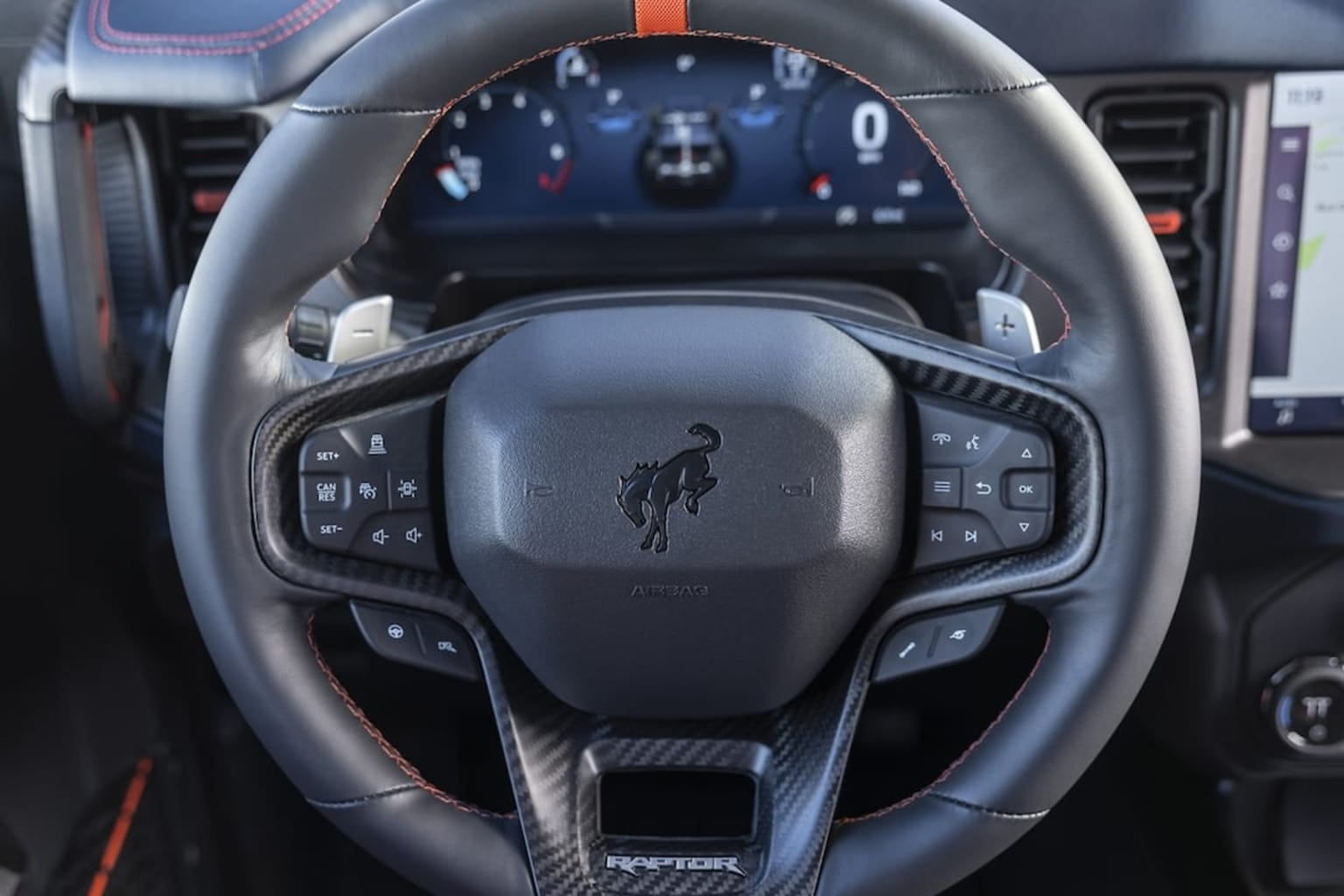 Interior of a high-performance sports car with a steering wheel featuring various controls and buttons, accompanied by a digital dashboard display in the background.