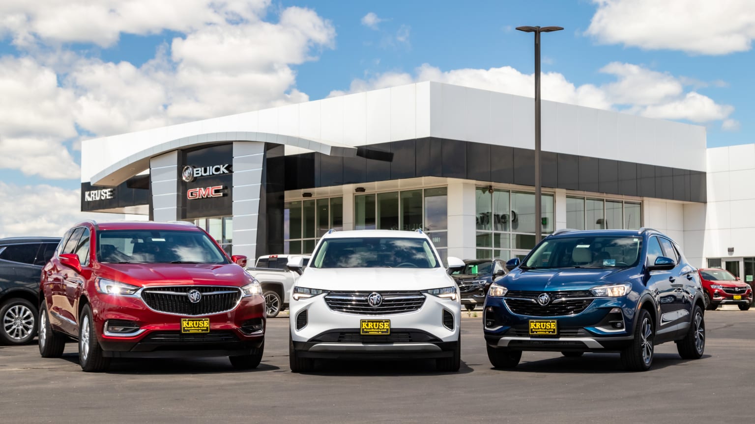 three cars are parked in front of a buick dealership in a parking lot in front of a building