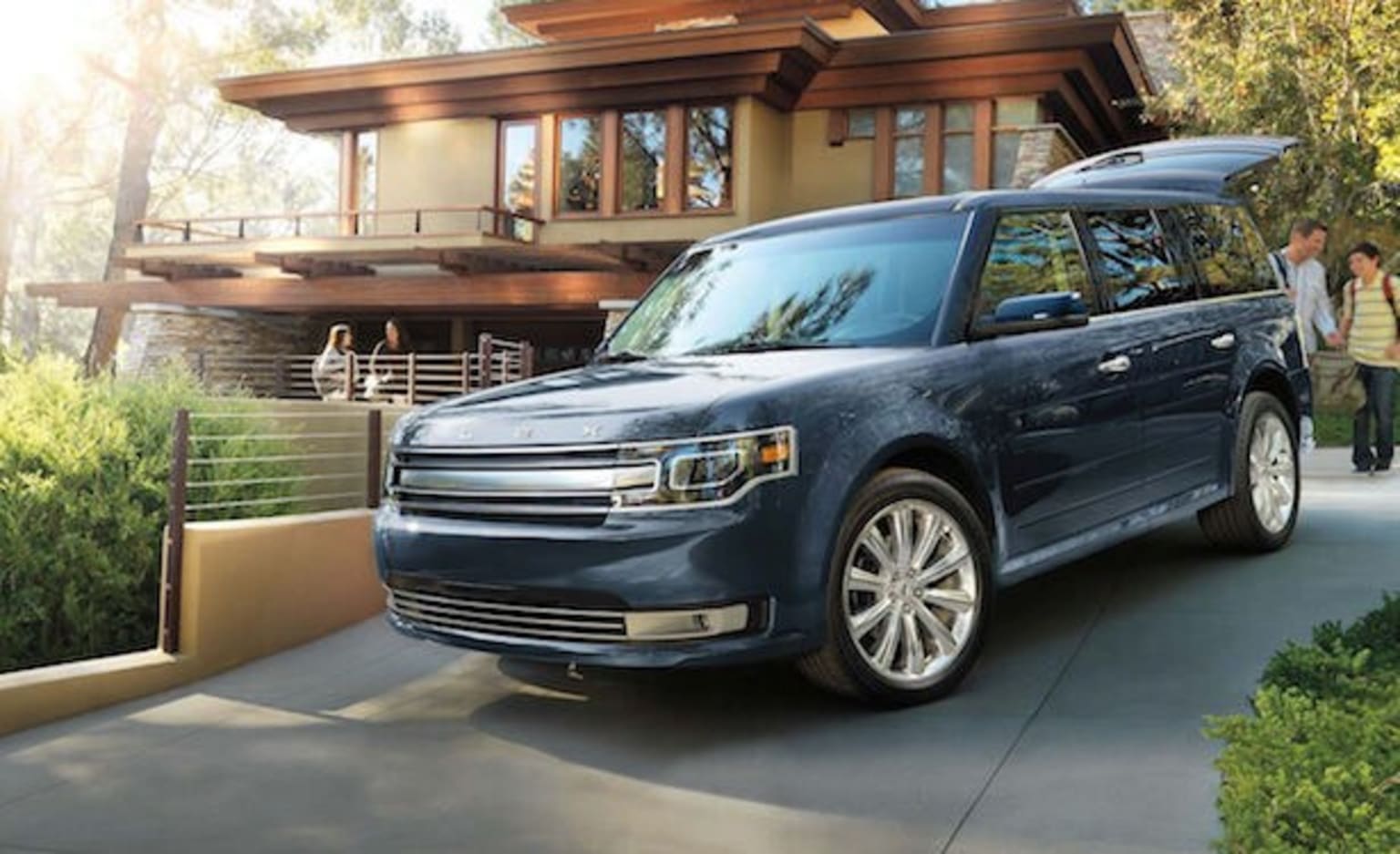a blue van is parked in front of a house with a man walking by it and a woman walking away from it