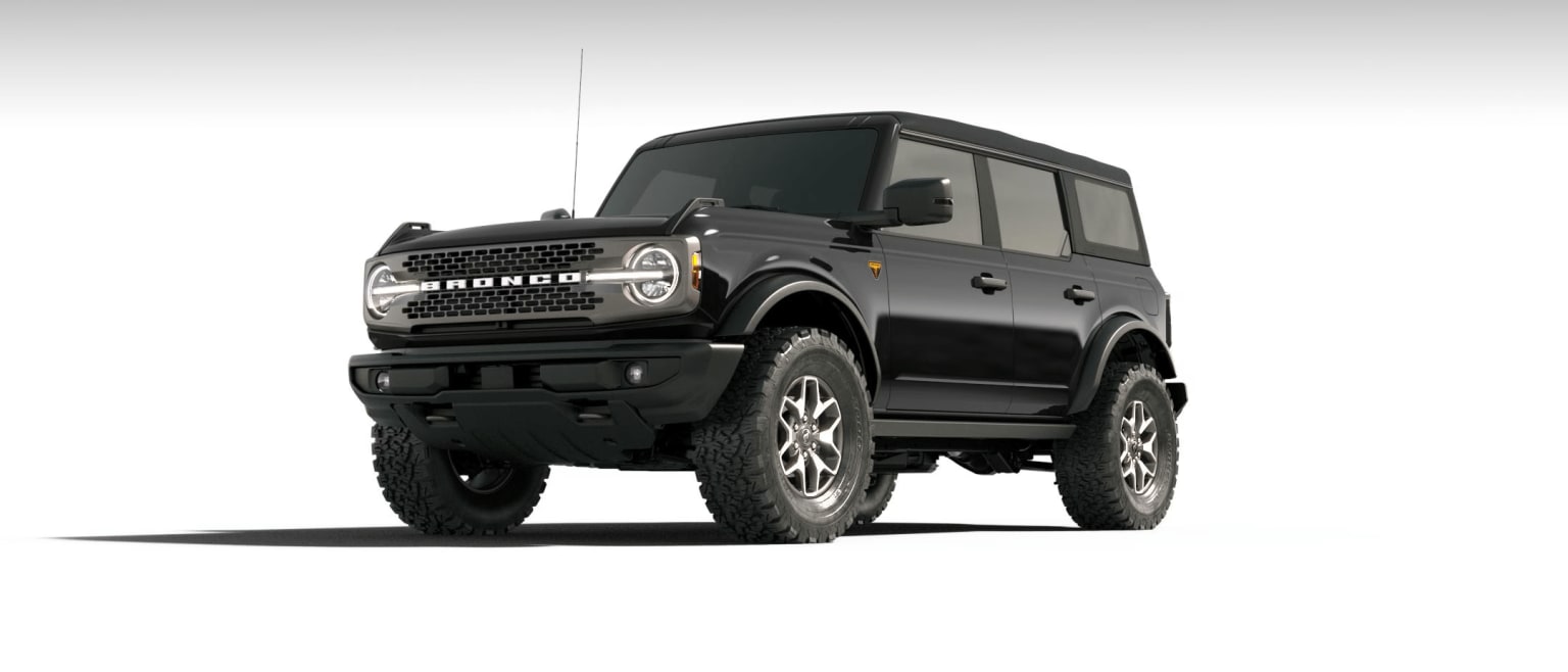 A rugged off-road vehicle with large tires and a boxy, angular design stands prominently in the frame against a plain background.