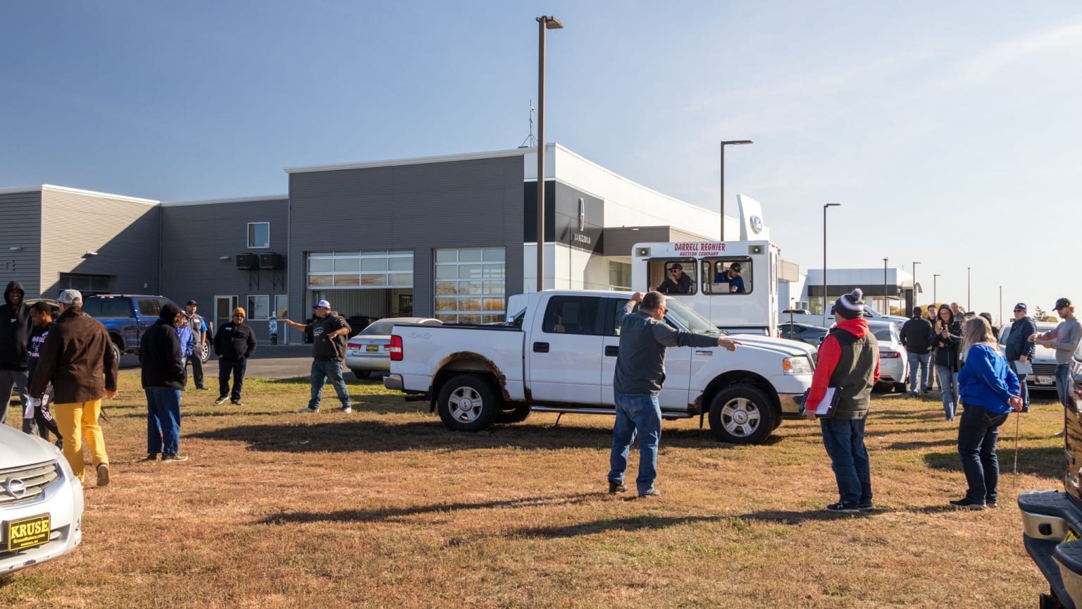 a group of people standing in front of a building with a white truck parked in front of it and a crowd of people standing around it