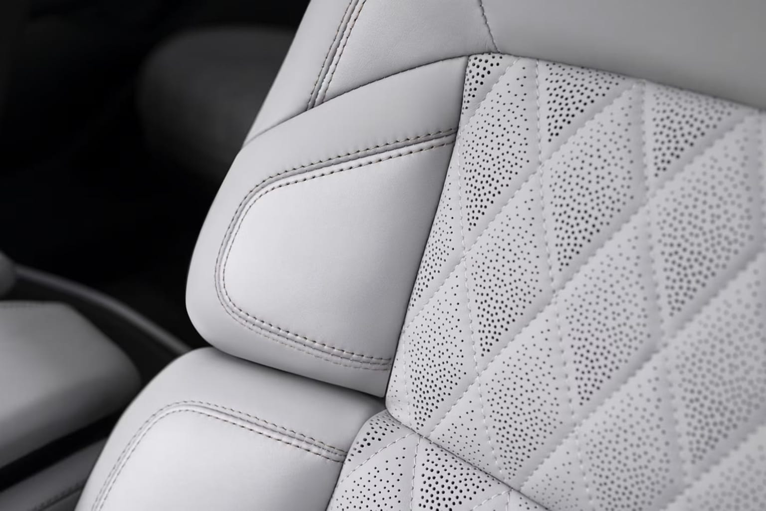 The image shows the interior of a vehicle, with a close-up view of the white leather upholstery and intricate stitching patterns on the seat.