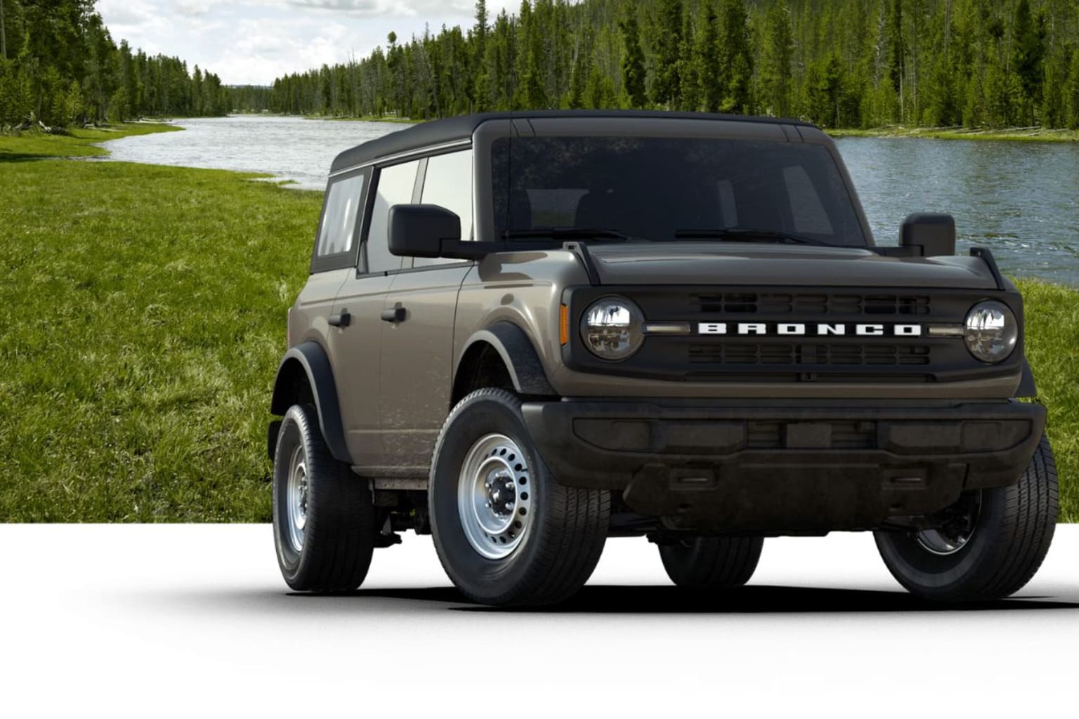 An off-road SUV in a lush green meadow surrounded by a dense forest and a river in the background.