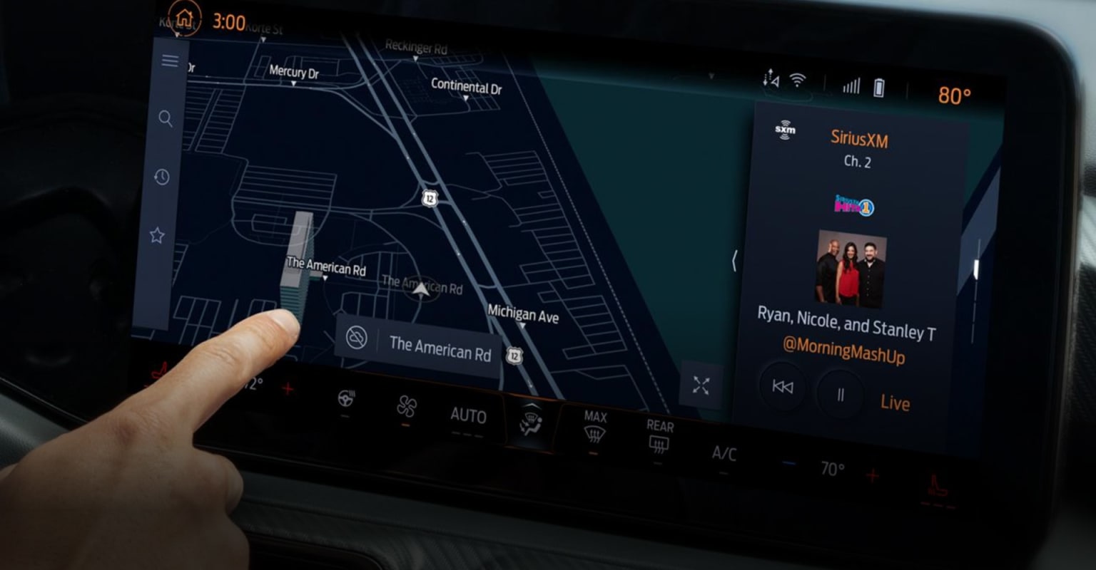 A hand interacting with a digital map display in the foreground against a dark vehicle-like interior.