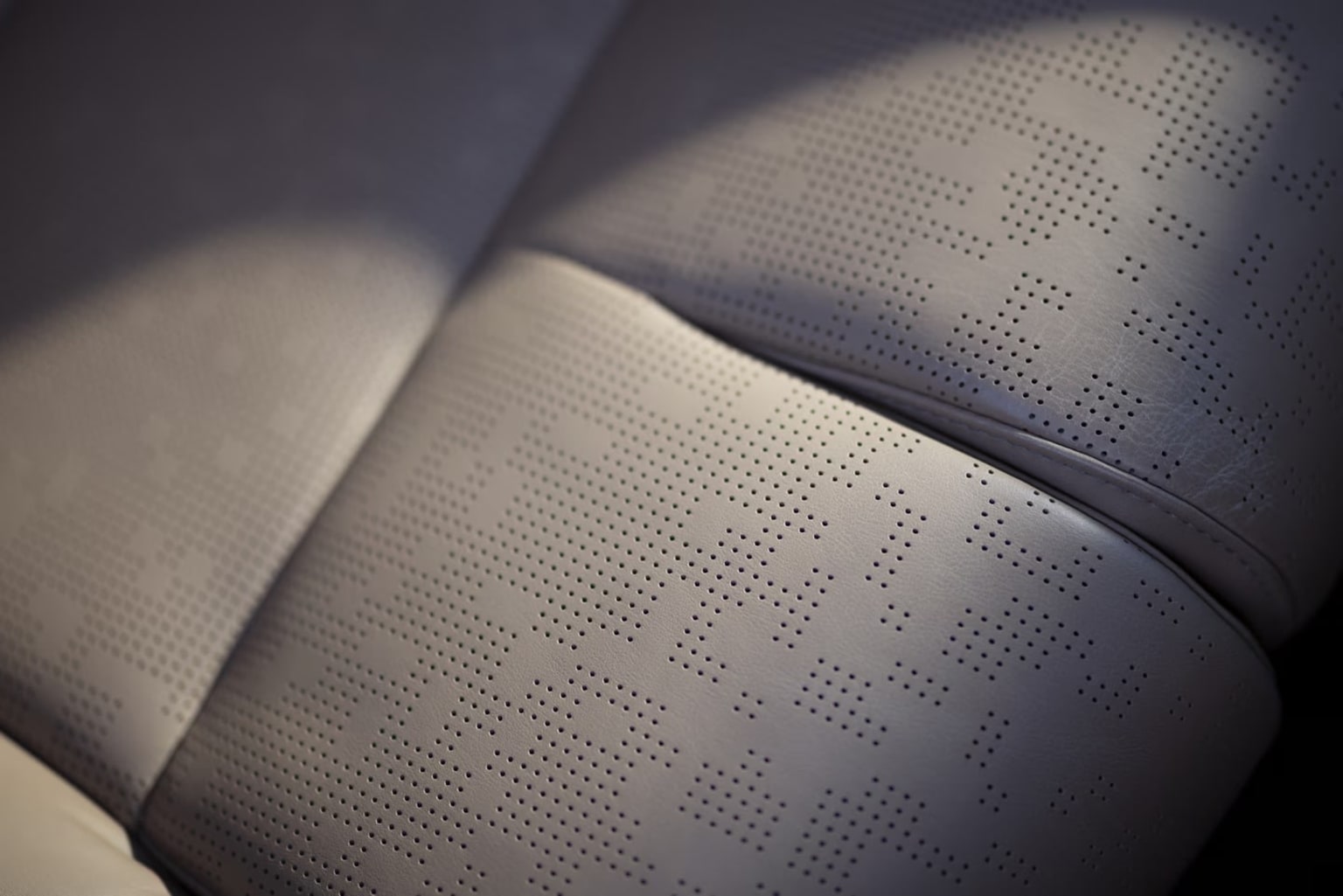 The image depicts a close-up view of a textured, perforated surface, with a soft, blurred background creating a sense of depth and focus on the intricate pattern.