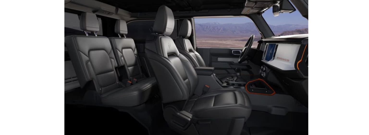 Interior of a large vehicle with comfortable leather seats and spacious layout, with a desert or mountainous landscape visible through the windows.