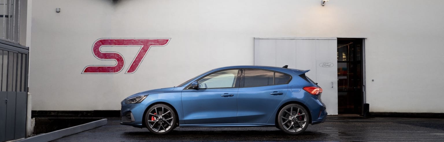 a blue car parked in front of a white building with a red s7 logo on the side of it