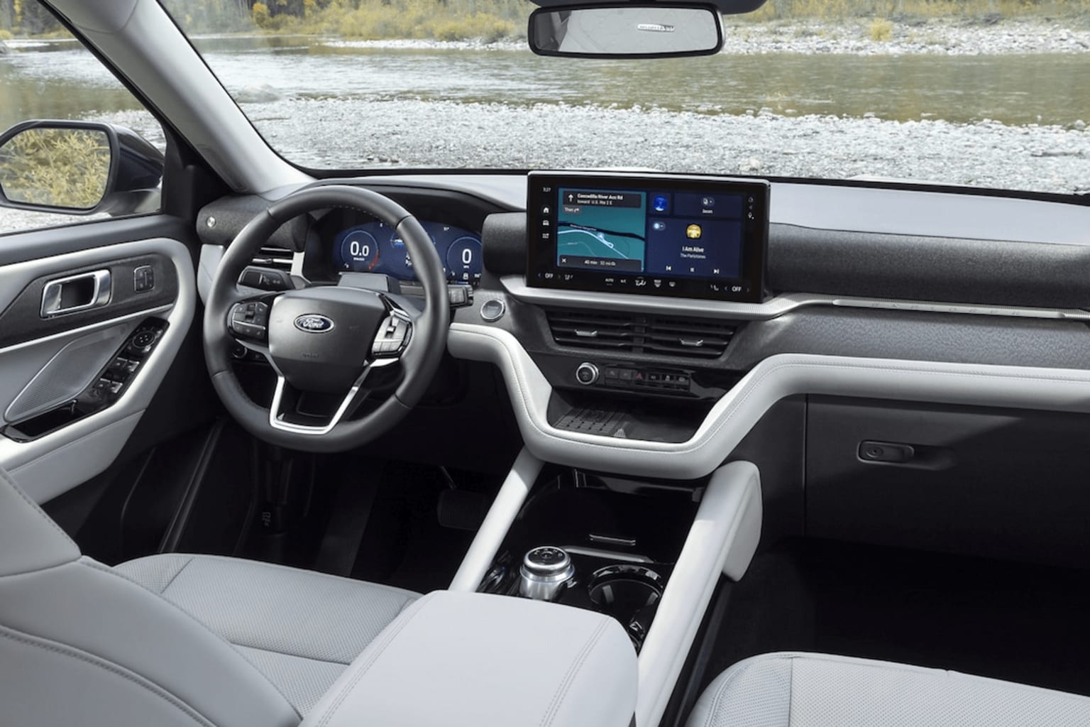 Interior of a modern vehicle with a large touchscreen display, steering wheel, and a view of a snowy outdoor landscape through the windshield.