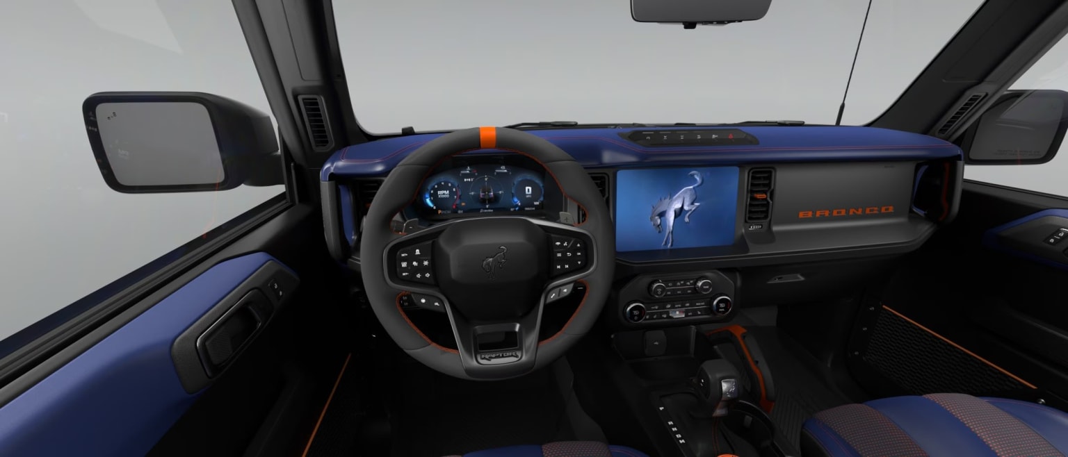 A car's steering wheel and dashboard with a large touchscreen against a plain white studio setting.
