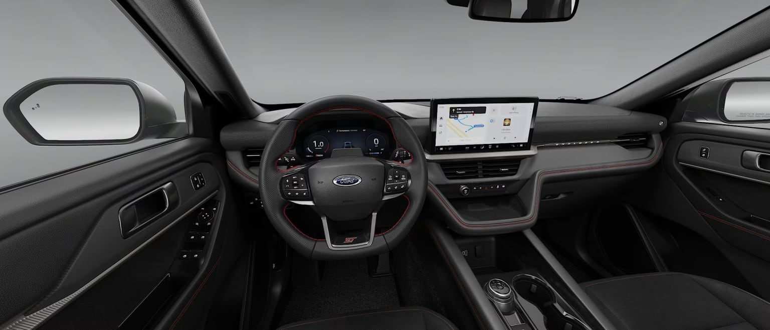Interior of a vehicle with a steering wheel, dashboard, and large touchscreen display in the center console.