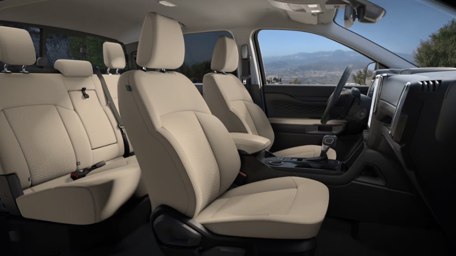 The image shows the interior of a vehicle, with rows of comfortable-looking beige seats and a scenic mountain landscape visible through the windshield in the background.