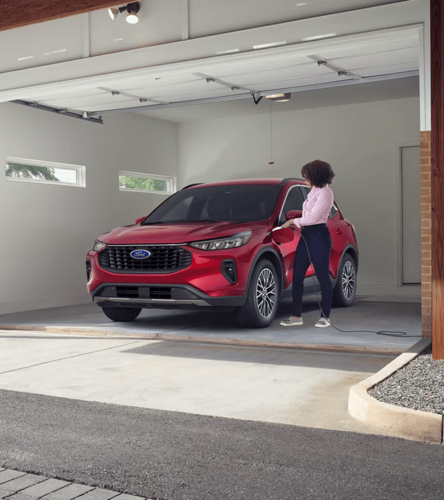 A person standing next to a red SUV in a garage with a concrete floor and white walls.