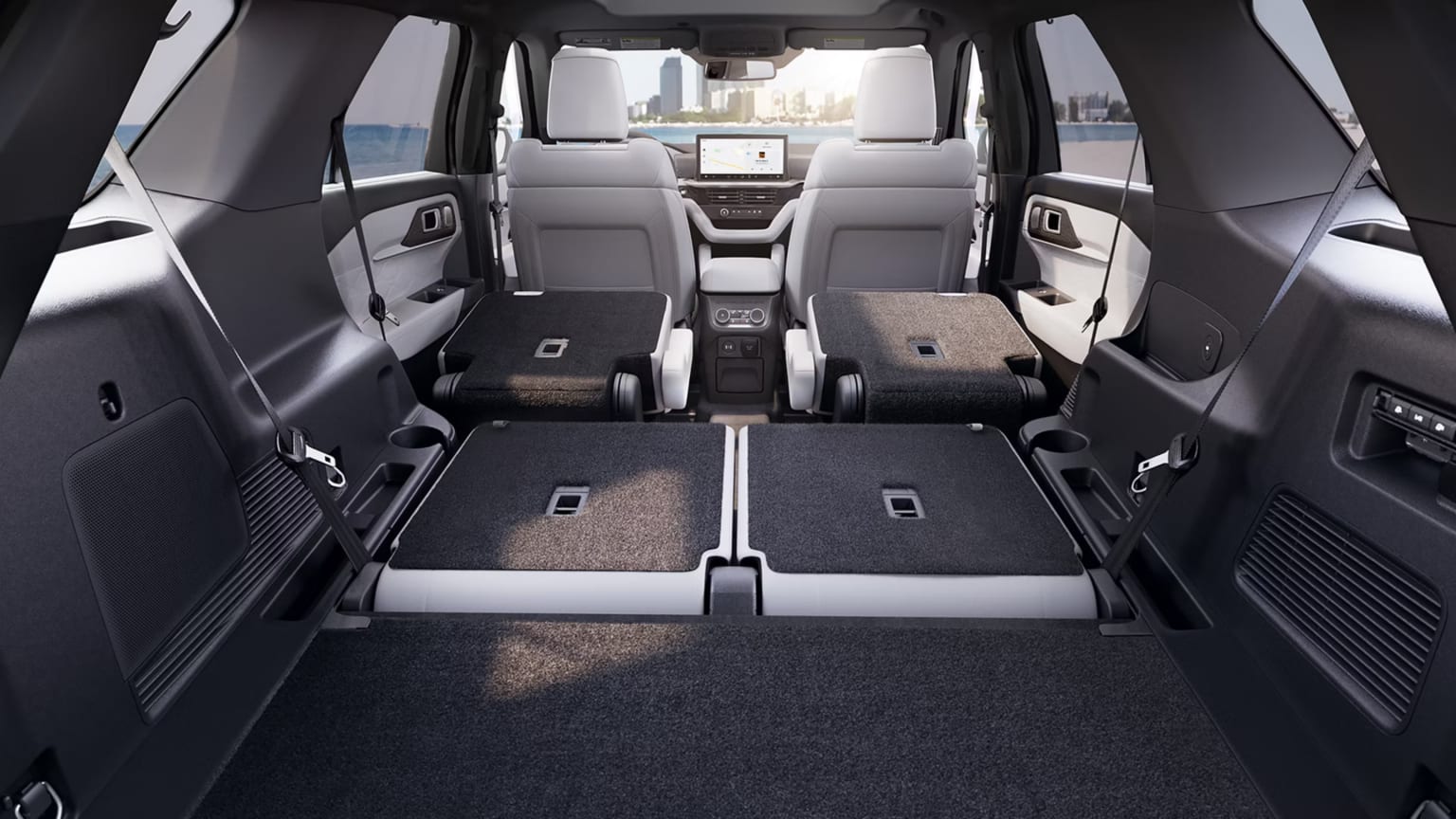 Spacious car interior with rear seats folded down, light-colored front seats, and a visible dashboard.