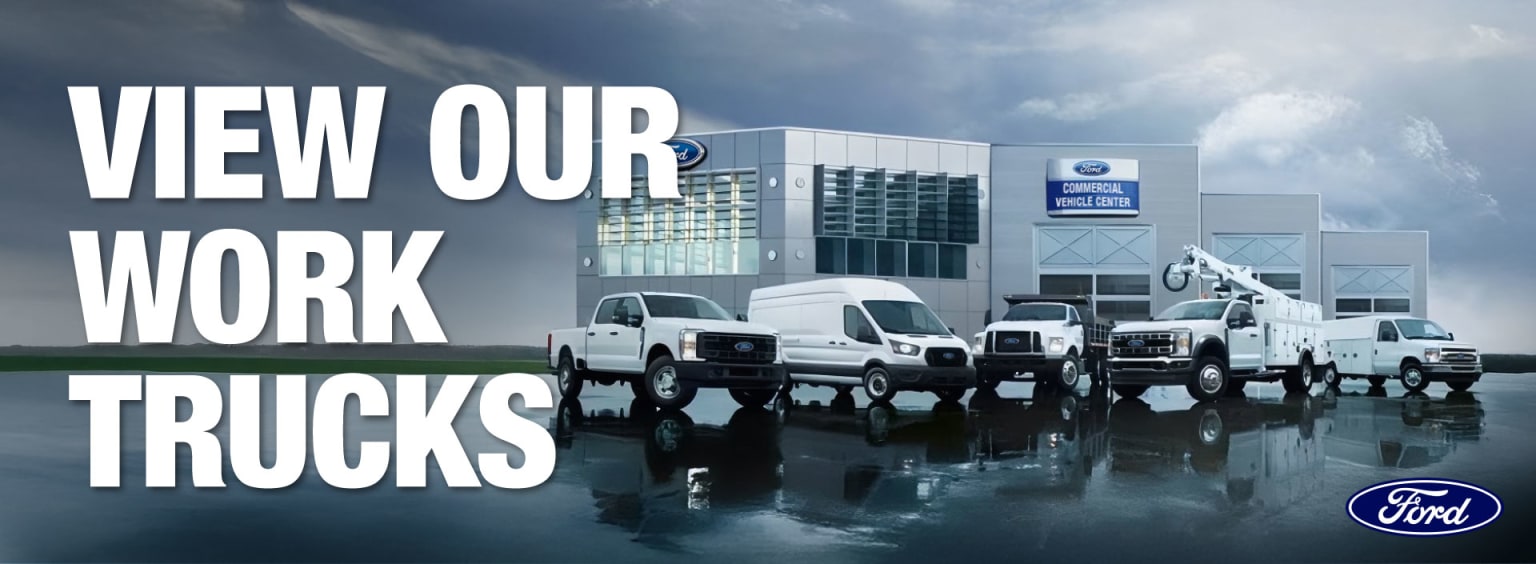 The image shows a dealership with several trucks parked in the foreground, and a large "NEW OUR WORK TRUCKS" sign prominently displayed on the building in the background.