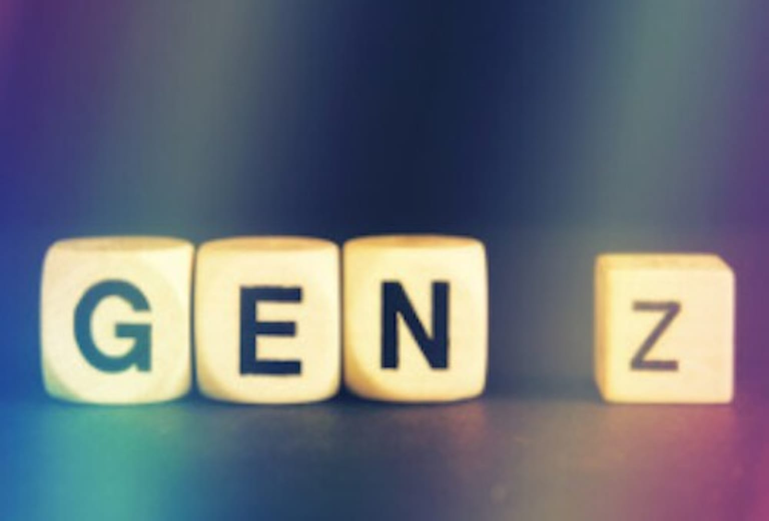 the word gen z spelled out with cubes on a colorful background with a blurry image of the word gen z