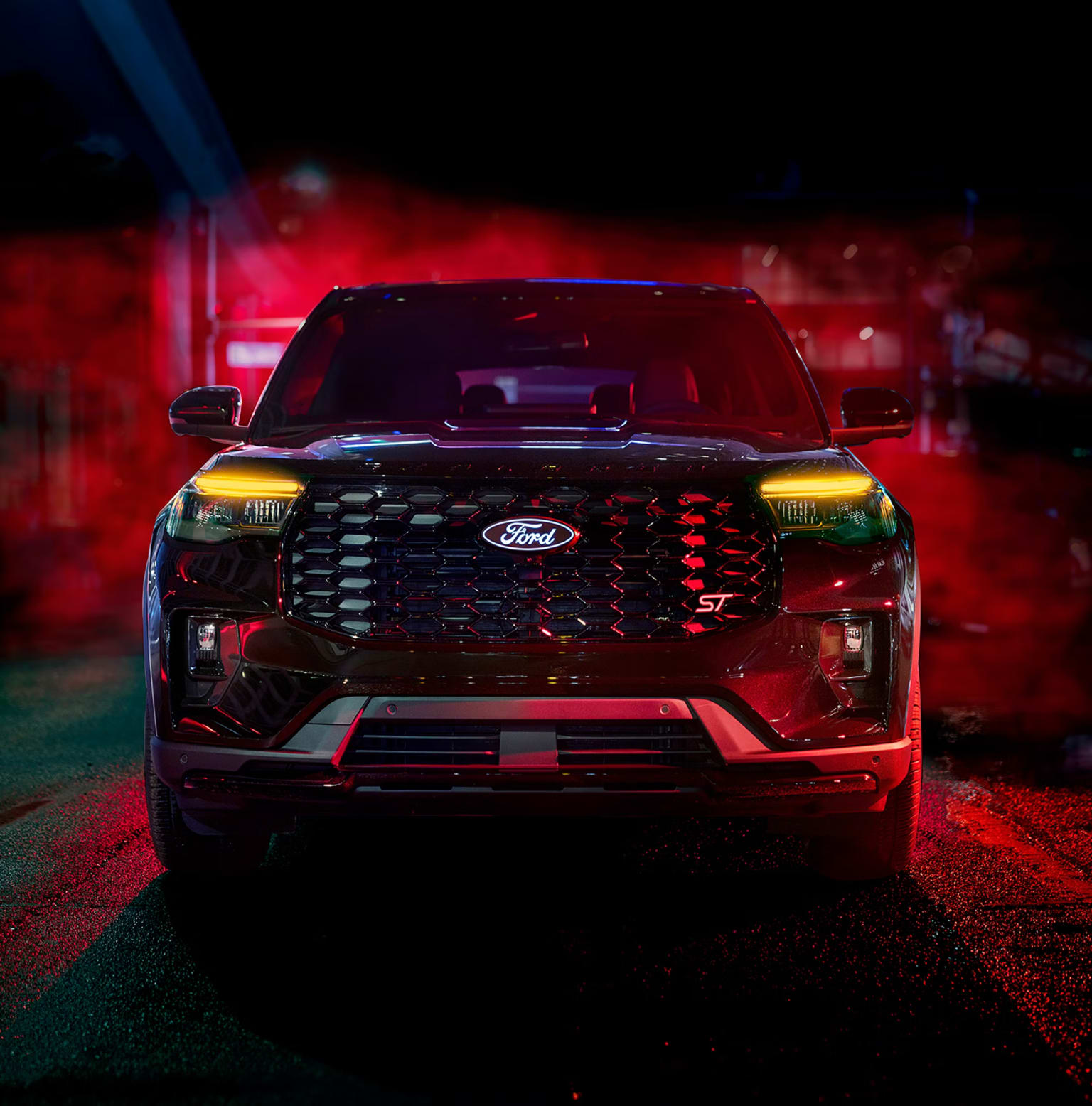 A black SUV stands in front of a dark background with red and blue lights.