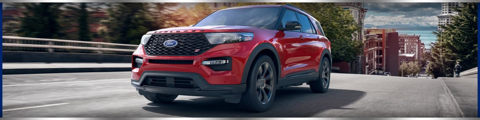 a red ford explorer is driving down the street in a city with trees and buildings in the background and the words ford written on the front of the front of the