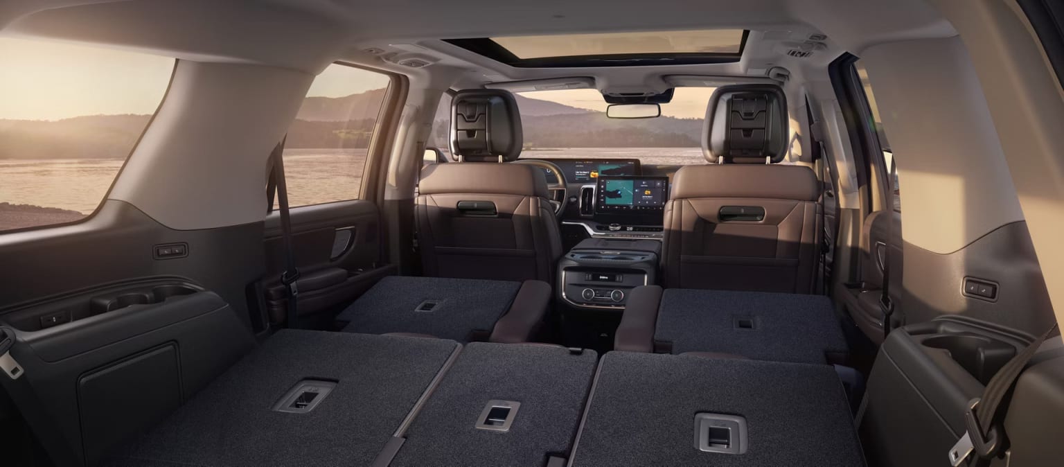 Interior of a spacious vehicle with large cargo area in the back and comfortable seating in the front. Dashboard features a large display screen, indicating the vehicle is equipped with advanced technology.