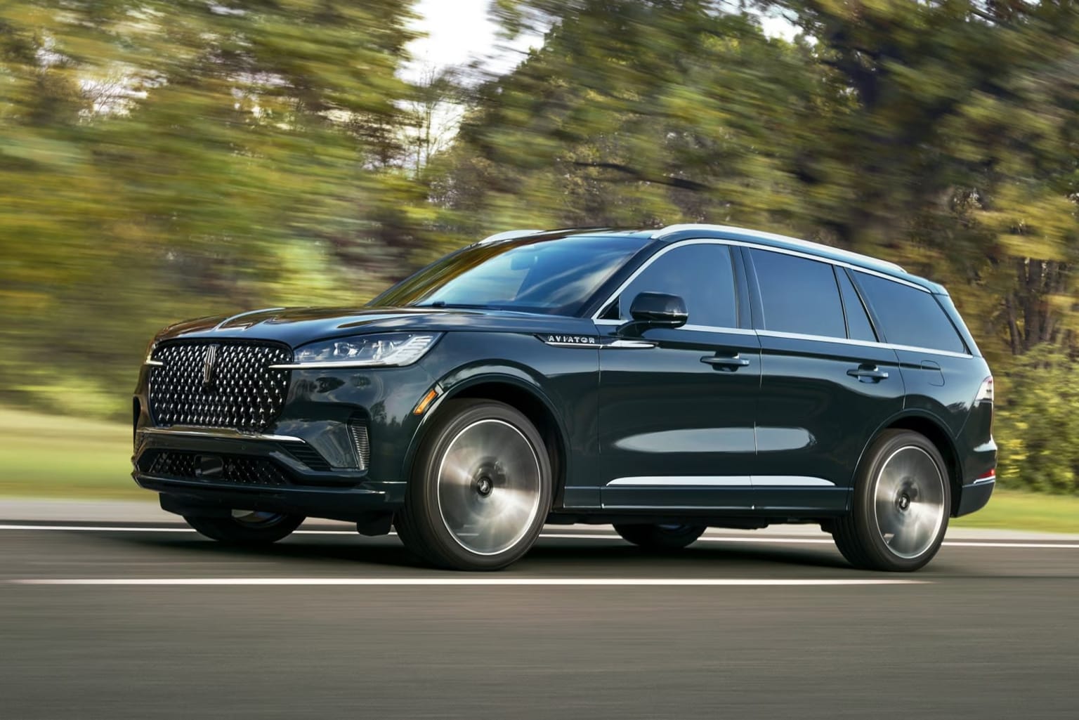 A sleek, black SUV speeding through a lush, forested landscape.