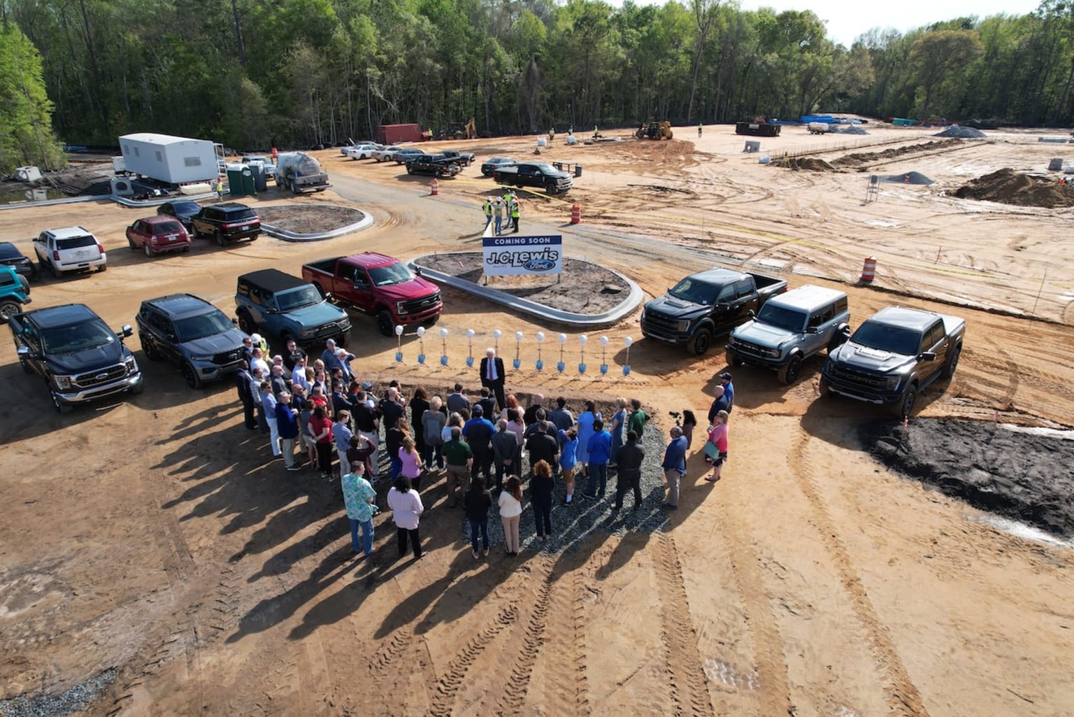 a group of people standing next to each other in front of a group of trucks on a dirt road