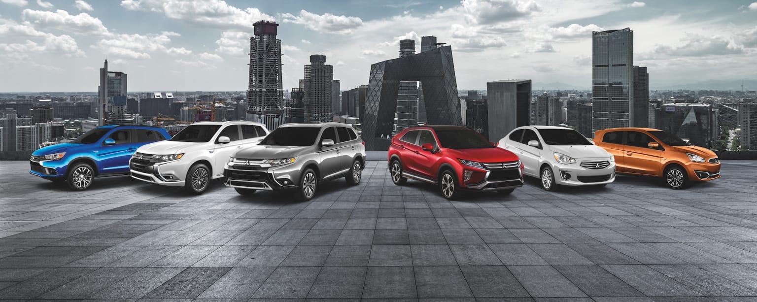 a group of four suvs parked in front of a cityscape with skyscrapers in the background