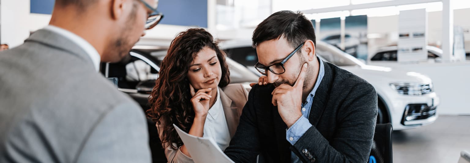A couple in a serious discussion in a professional setting with cars in the background.