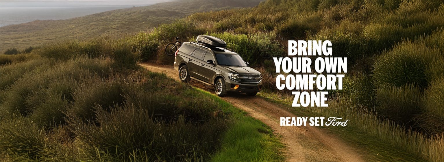 A rugged off-road vehicle navigates a dirt path through a lush, hilly landscape, with the text "Bring your own comfort zone" prominently displayed.