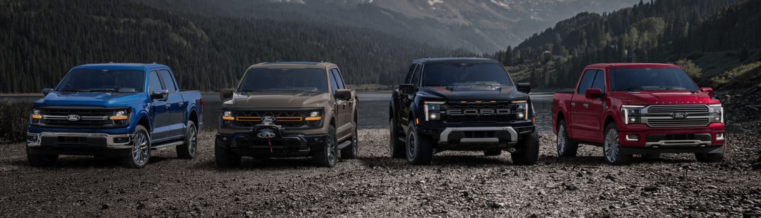 Off-road vehicles parked on a dirt road in a mountainous, forested landscape.