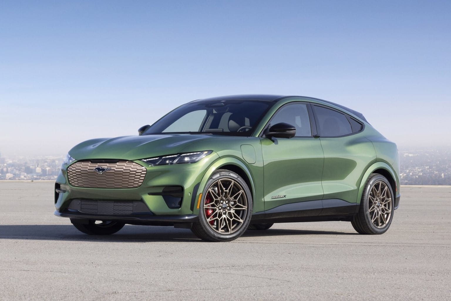 Electric SUV in green color on a paved road with clear blue sky in the background