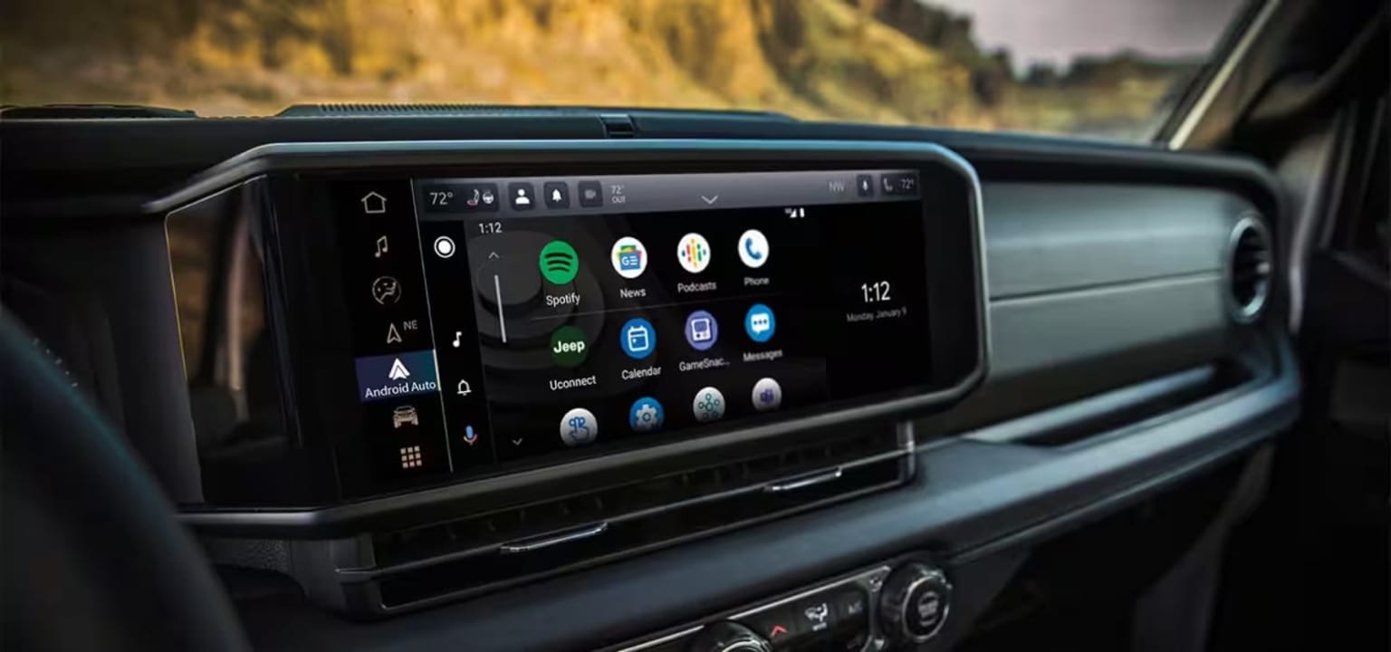 The image shows the interior of a vehicle with a large touchscreen display in the center console displaying various icons and information.