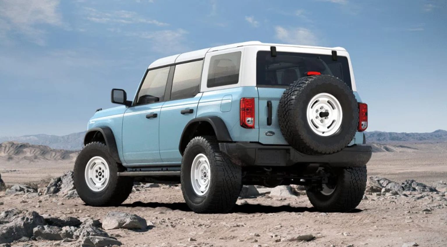 Off-road vehicle in desert landscape with rocky terrain and clear blue sky