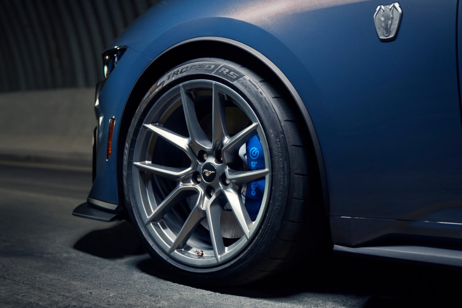 a close up of a car tire on a dark surface with a building in the backgrouund