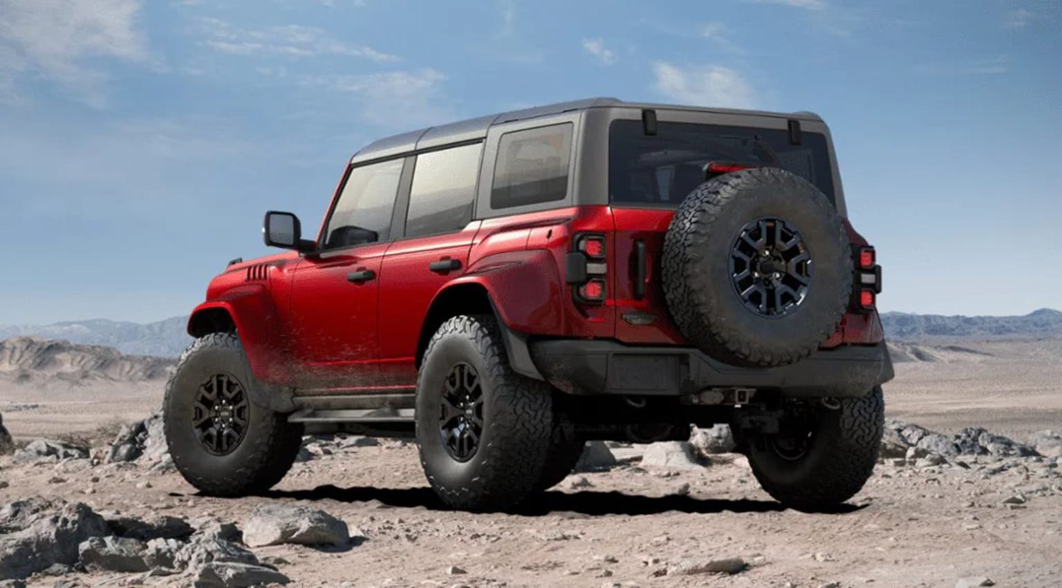 An off-road vehicle with large tires and a rugged exterior is parked on a rocky, desert-like terrain against a backdrop of a clear blue sky.