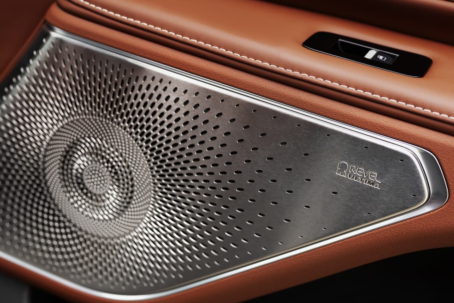 Close-up view of a speaker grill with a perforated metal surface against a warm, leather-like background.