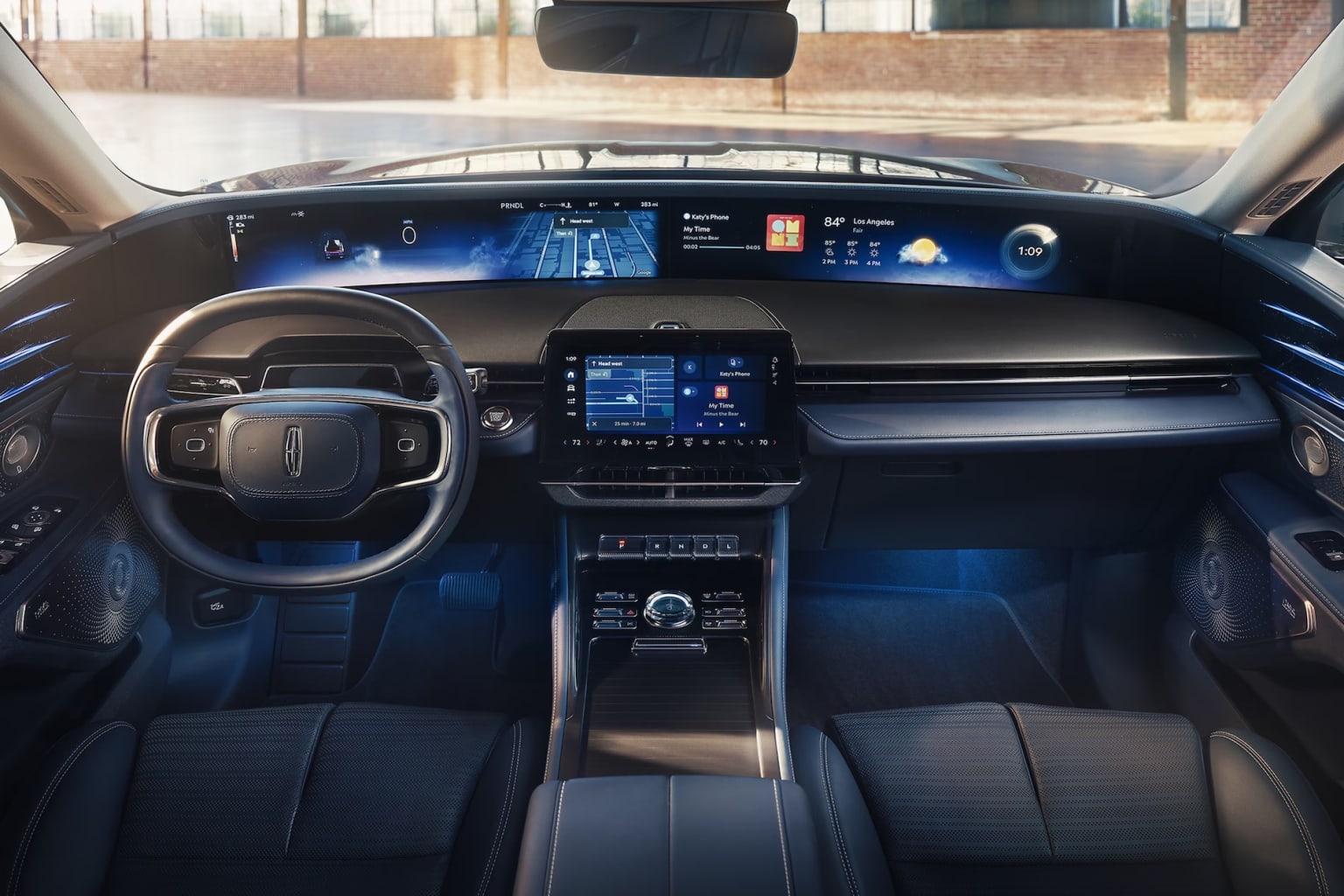 The image shows the interior of a modern vehicle with a sleek and futuristic dashboard featuring a large digital display, various controls, and a steering wheel.