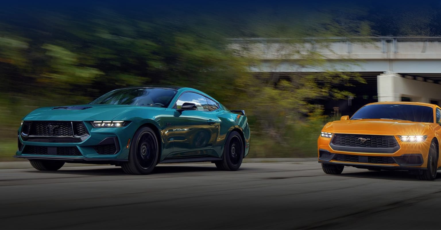 Two high-performance SUVs, one in a vibrant teal color and the other in a bold orange, are captured in motion against a blurred background, suggesting a dynamic and powerful driving experience.
