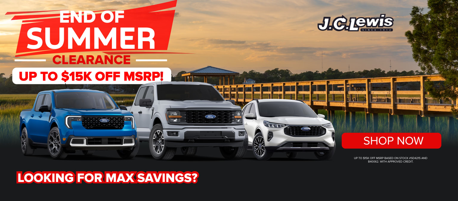 This image shows a car dealership advertisement for an "End of Summer Clearance" event, featuring various trucks and SUVs in the foreground against a scenic background of a sunset sky and a body of water.