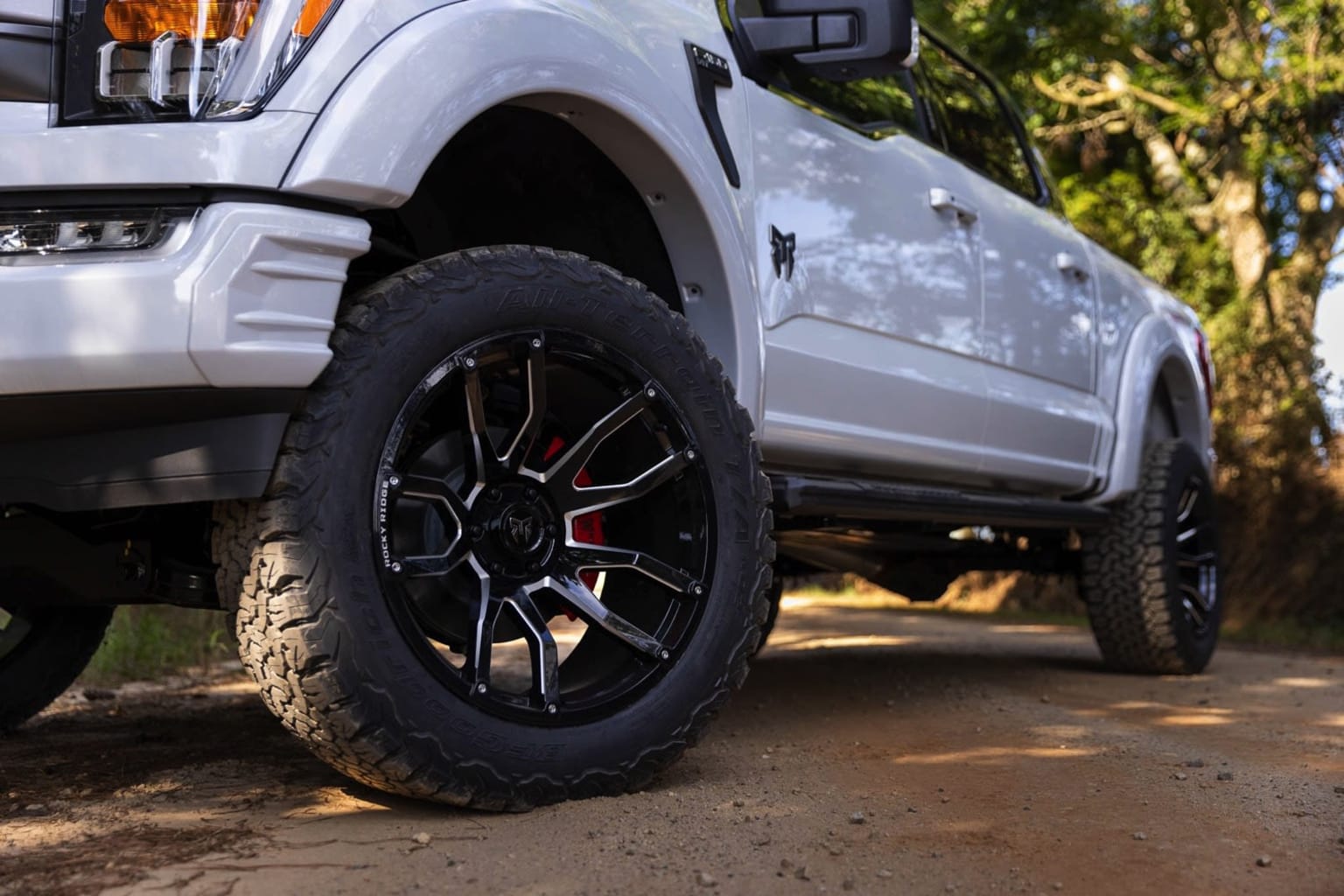 Off-road vehicle with rugged tires on dirt path surrounded by greenery.
